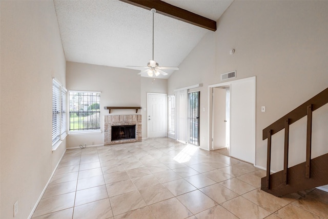 unfurnished living room with light tile patterned floors, a ceiling fan, visible vents, beam ceiling, and a fireplace