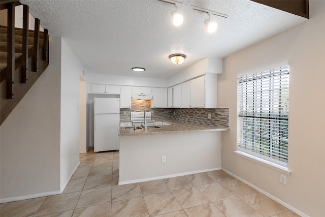 kitchen featuring white appliances, backsplash, a peninsula, and white cabinetry