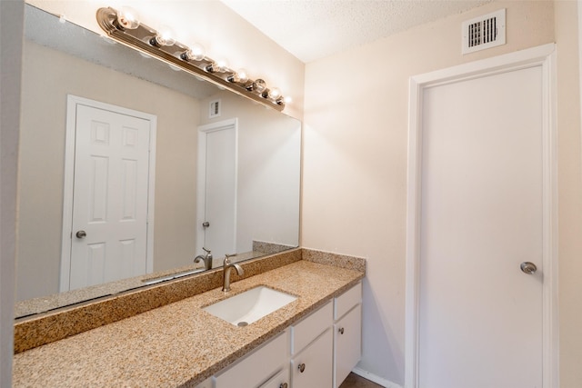 bathroom with visible vents, a textured ceiling, and vanity