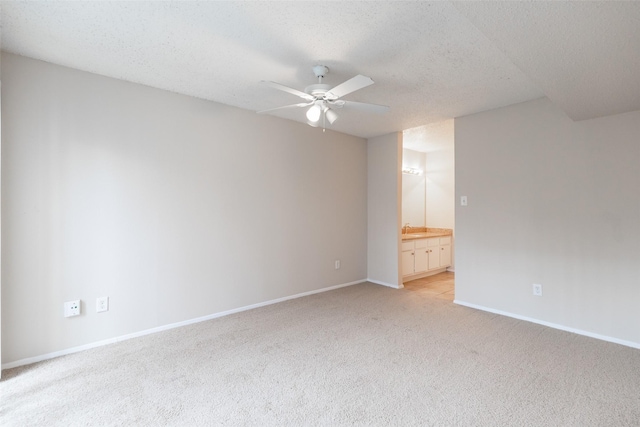 unfurnished room with baseboards, light colored carpet, a textured ceiling, and a ceiling fan