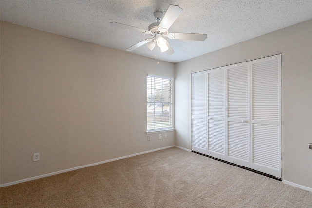 unfurnished bedroom with baseboards, carpet floors, ceiling fan, a closet, and a textured ceiling