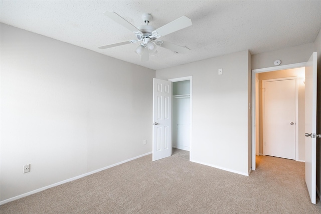 unfurnished bedroom featuring light colored carpet, a textured ceiling, and baseboards