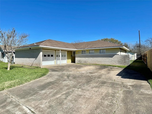 view of front of house featuring a front lawn, driveway, fence, a garage, and brick siding