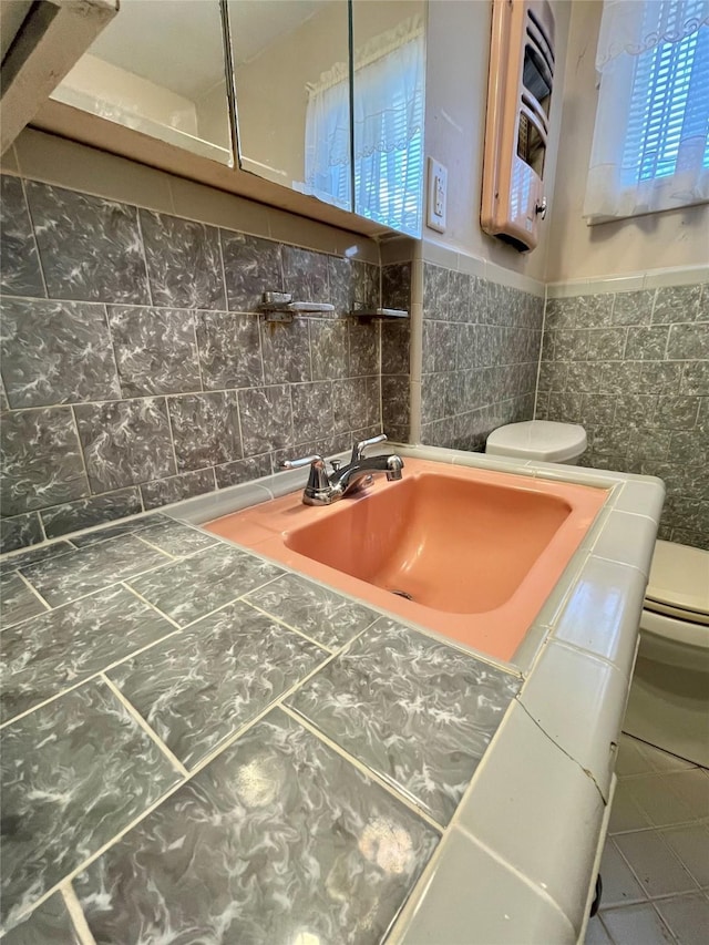 bathroom with toilet, tile walls, wainscoting, tile patterned flooring, and vanity