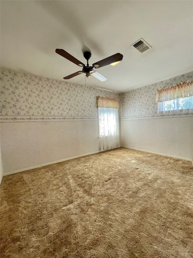 unfurnished room featuring wallpapered walls, carpet, visible vents, and a ceiling fan