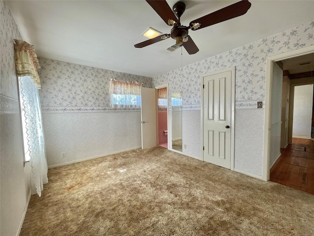 unfurnished bedroom with visible vents, ceiling fan, carpet flooring, and wallpapered walls