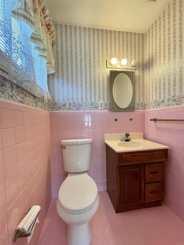 half bath featuring tile patterned floors, a wainscoted wall, toilet, and wallpapered walls