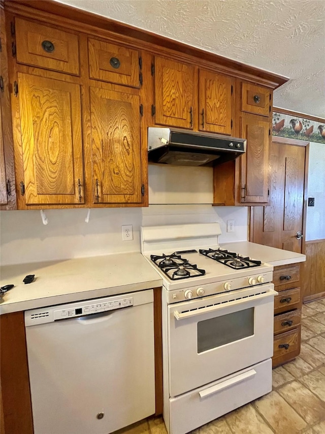 kitchen with under cabinet range hood, white appliances, brown cabinets, and light countertops