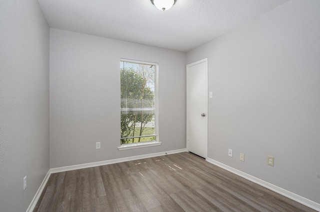 empty room featuring plenty of natural light, baseboards, and wood finished floors