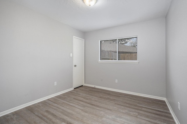 empty room featuring baseboards, a textured ceiling, and wood finished floors