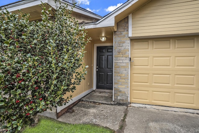 doorway to property with an attached garage and stone siding