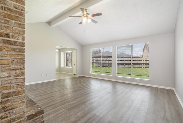 unfurnished living room featuring baseboards, lofted ceiling with beams, a ceiling fan, and wood finished floors