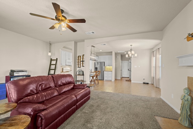 living area featuring light tile patterned floors, visible vents, arched walkways, light carpet, and ceiling fan with notable chandelier