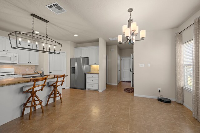 14864 Cetus Ct, Willis, TX 77318 - kitchen featuring white appliances, a chandelier, a sink, tasteful backsplash, and white cabinetry