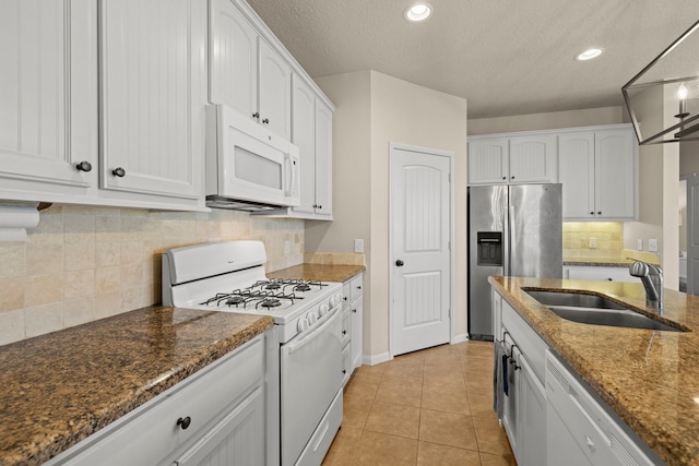 kitchen featuring white cabinetry, white appliances, light tile patterned flooring, and a sink