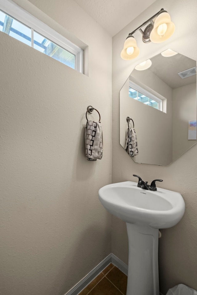 bathroom with tile patterned flooring, visible vents, baseboards, and a wealth of natural light