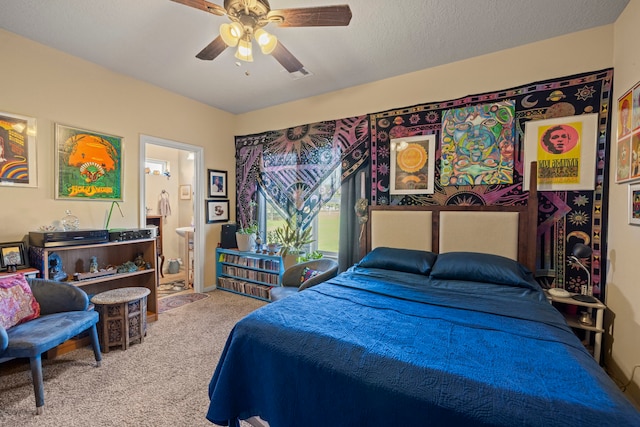 bedroom featuring a textured ceiling, ensuite bath, carpet floors, and ceiling fan