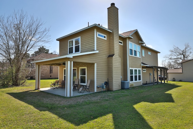 rear view of house featuring a patio, cooling unit, a lawn, and a chimney