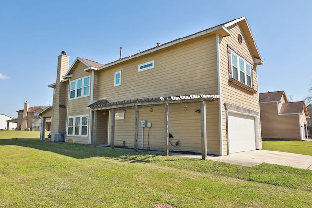 rear view of property with cooling unit, an attached garage, a chimney, concrete driveway, and a lawn