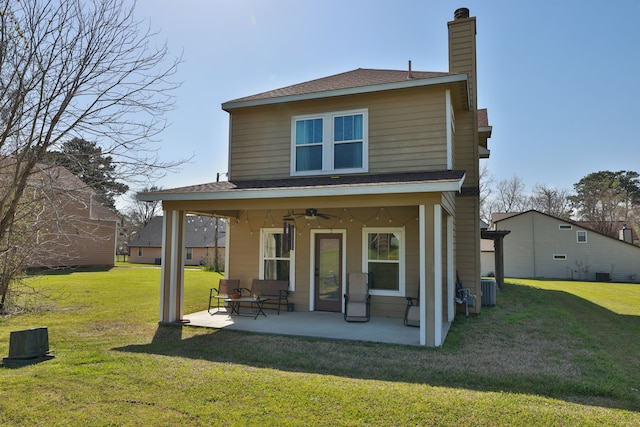 back of house with central air condition unit, a patio, a yard, ceiling fan, and a chimney