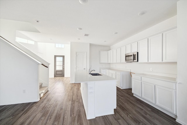 kitchen featuring a sink, stainless steel microwave, visible vents, and white cabinetry