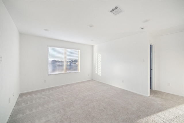 unfurnished room featuring visible vents, baseboards, and light colored carpet