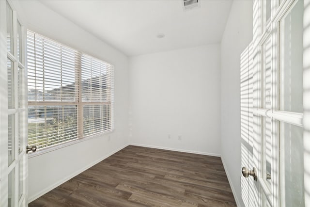 spare room with visible vents, baseboards, and dark wood-style flooring