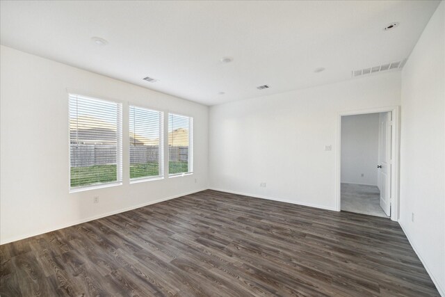 spare room with dark wood finished floors, visible vents, and baseboards