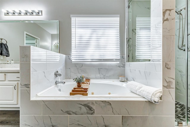 full bathroom with a marble finish shower, a jetted tub, and vanity