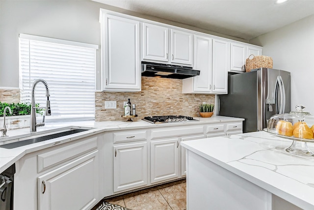 kitchen with backsplash, under cabinet range hood, white cabinets, stainless steel appliances, and a sink