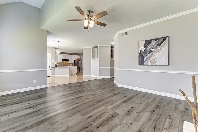 unfurnished living room featuring a ceiling fan, baseboards, visible vents, light wood-style flooring, and ornamental molding