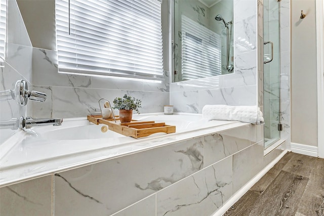 bathroom featuring a marble finish shower, plenty of natural light, a garden tub, and wood finished floors