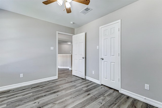 unfurnished bedroom with visible vents, baseboards, wood finished floors, and a ceiling fan