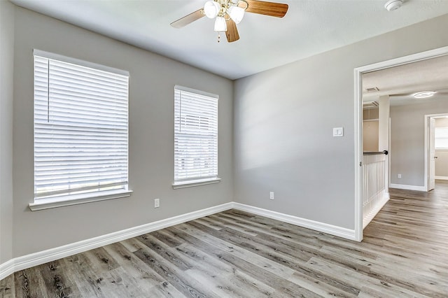 empty room with wood finished floors, baseboards, and ceiling fan