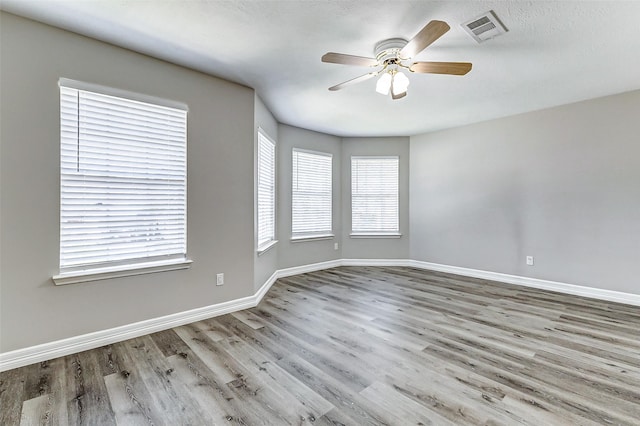 unfurnished room with visible vents, baseboards, wood finished floors, and a ceiling fan