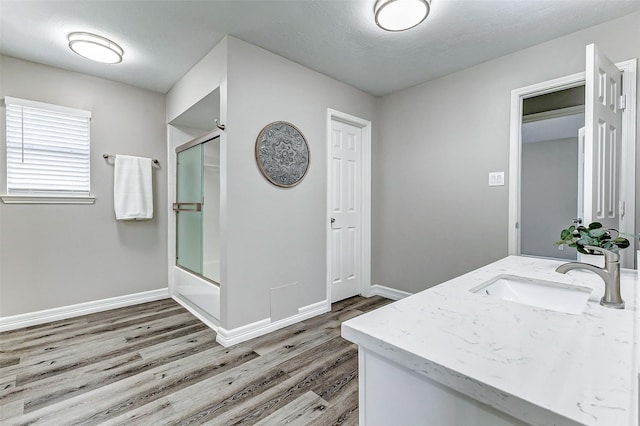 full bath featuring baseboards, enclosed tub / shower combo, wood finished floors, and vanity