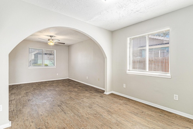 unfurnished room with baseboards, a textured ceiling, ceiling fan, and wood finished floors