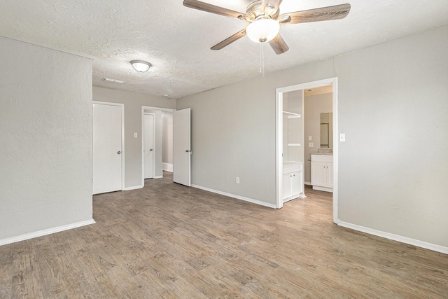 unfurnished room featuring ceiling fan, baseboards, a textured ceiling, and light wood-style flooring