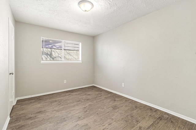 spare room featuring baseboards, a textured ceiling, and wood finished floors