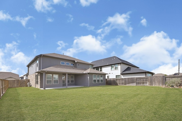 back of property featuring a yard, a patio, roof with shingles, and a fenced backyard