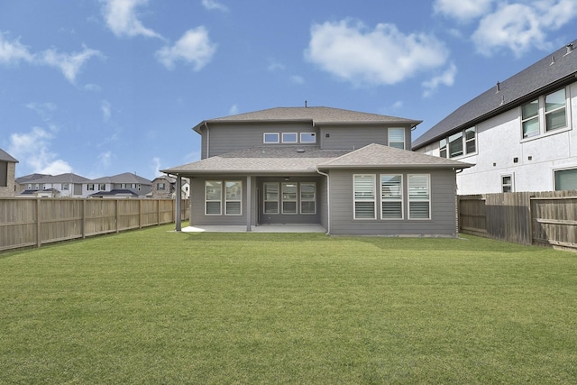 rear view of property featuring a patio, a lawn, a fenced backyard, and a shingled roof