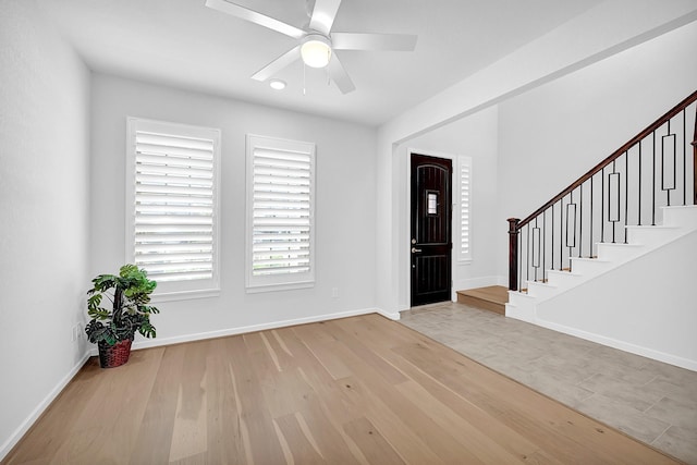 entryway featuring stairs, a ceiling fan, light wood-type flooring, and baseboards