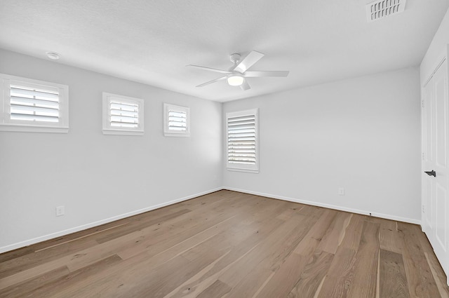 unfurnished room with visible vents, baseboards, ceiling fan, and wood finished floors