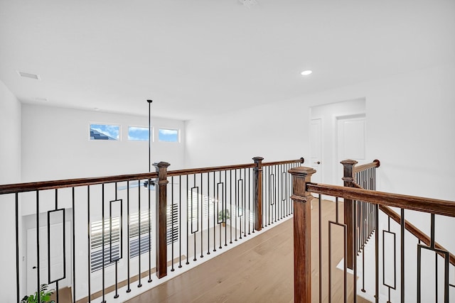 hall with light wood-type flooring, visible vents, an upstairs landing, and recessed lighting