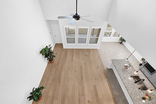 unfurnished living room featuring baseboards, wood finished floors, and ceiling fan