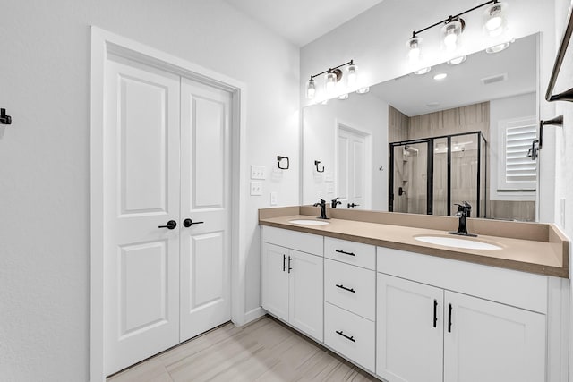 bathroom with double vanity, visible vents, a shower stall, and a sink