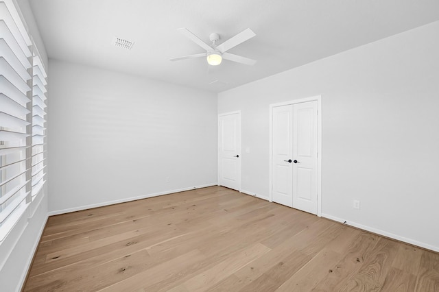 unfurnished bedroom featuring baseboards, visible vents, a ceiling fan, and light wood-style floors