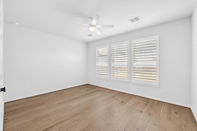 spare room featuring visible vents, baseboards, ceiling fan, and wood finished floors