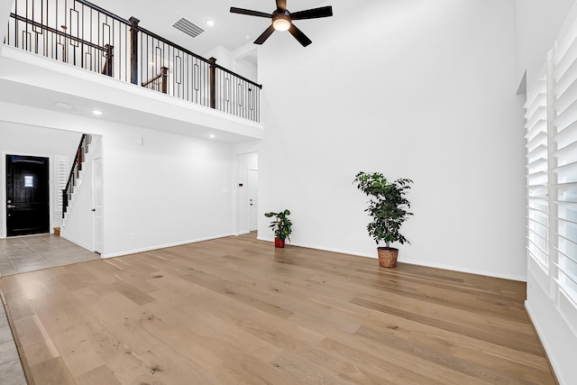 unfurnished living room with visible vents, light wood-style flooring, baseboards, and ceiling fan