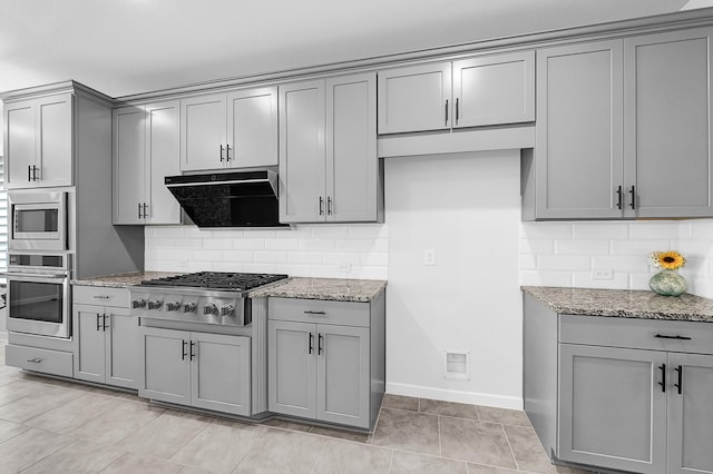 kitchen featuring light stone counters, gray cabinets, extractor fan, appliances with stainless steel finishes, and backsplash